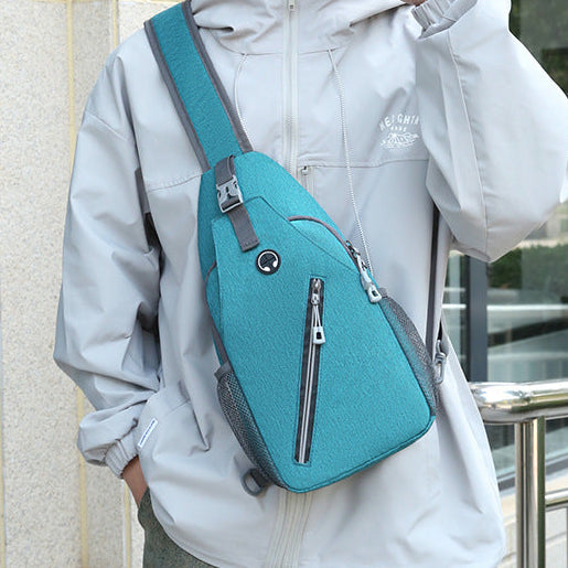 Person wearing a light gray jacket with a teal crossbody bag outdoors.