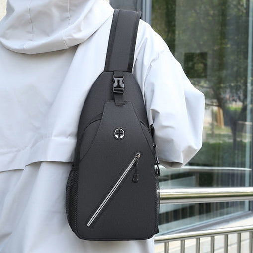 Person wearing a black sling bag outdoors near a building